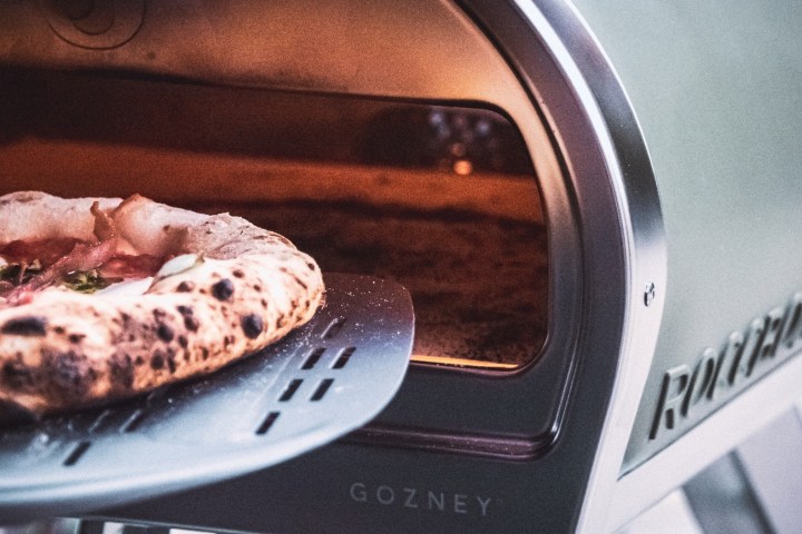 Pizza being removed from a Gozney Roccbox portable pizza oven.