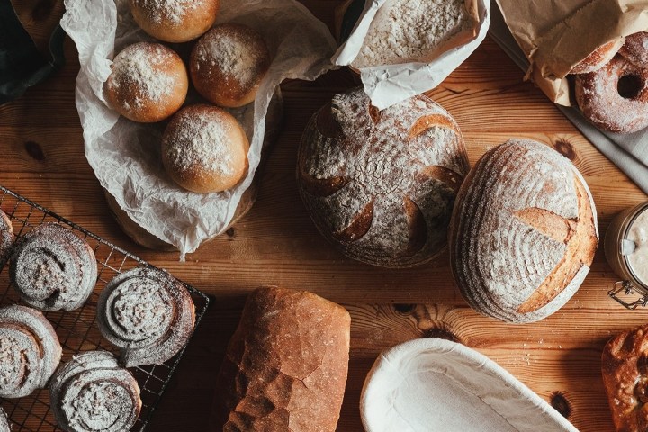 Variety of artisanal breads and pastries on a wooden table.